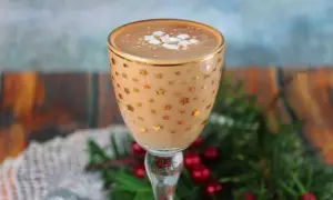 Kukułka alkohol w kieliszku w gwiazdki, ozdobiona pianką i posypką. W tle świąteczne dekoracje.