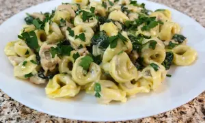Tortellini z ricottą i szpinakiem w kremowym sosie, posypane natką pietruszki. Idealne danie, które można podawać samo lub z dodatkiem kurczaka.