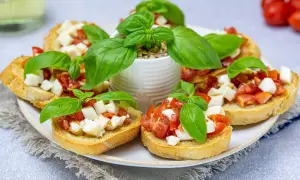 Przepis na bruschettę z pomidorami i mozzarellą: chrupiące grzanki z soczystymi pomidorami i kremową mozzarellą, ozdobione świeżą bazylią.