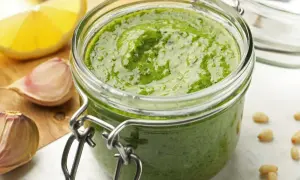 Domowe pesto w słoiku, obok czosnek i cytryna. Czy pesto ze słoika się podgrzewa? Zwykle nie, ale to zależy od przepisu.