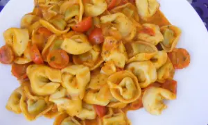 Pyszne tortellini ze szpinakiem w kremowym sosie pomidorowym z kawałkami pomidorków.