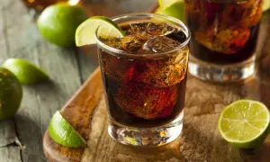 Orzeźwiający drink z rumem Bacardi Raspberry, lodem i limonką na drewnianej desce.