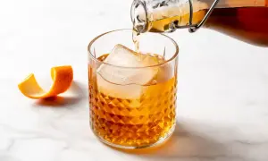 Bursztynowy drink z lodem i skórką pomarańczy, nalewany z butelki. Czuć w nim subtelny smak amaretto.