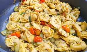 Pyszne tortellini z serem, podsmażane z cukinią i pomidorkami koktajlowymi, doprawione ziołami.