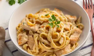 Pyszne fettuccine z kurczakiem w kremowym, oryginalnym sosie alfredo, udekorowane natką pietruszki.