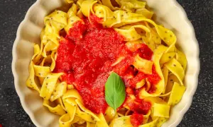 Pappardelle, czyli gruby makaron spaghetti, polane sosem pomidorowym i udekorowane listkiem bazylii.