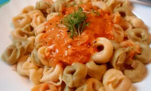 Kolorowe tortellini w kremowym sosie pomidorowym, udekorowane świeżą rukolą. Pyszny sos do tortellini kusi aromatem.