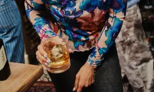 Kobieta trzyma szklankę z whisky Ballantine's. Zastanawia się, ile procent ma ten wyborny trunek.