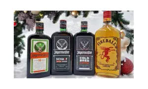 Cztery butelki alkoholu: Jägermeister (w tym czarny alkohol), Jägermeister Spiced Ginger, Jägermeister Cold Brew Coffee i Fireball, na tle świątecznych dekoracji.