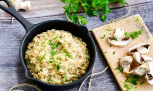 Kremowe włoskie risotto z grzybami, posypane natką pietruszki. Idealny przepis na pyszny obiad.
