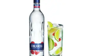 Butelka Finlandia Raspberry i szklanka z drinkiem, lodem, limonką i malinami. Idealny alkohol na letnie wieczory.