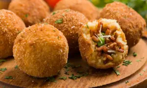 Chrupiące arancini, pyszne włoskie dania mięsne, z bogatym nadzieniem mięsnym i groszkiem, posypane parmezanem.