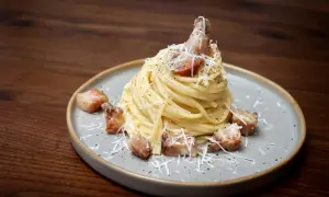 Pyszne spaghetti carbonara z chrupiącym guanciale, posypane parmezanem i świeżo mielonym pieprzem.