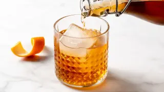 Bursztynowy drink z lodem i skórką pomarańczy, nalewany z butelki. Czuć w nim subtelny smak amaretto.