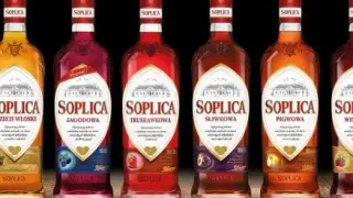 Rząd butelek Soplicy: jagodowa, truskawkowa, śliwkowa, pigwowa i inne smaki.