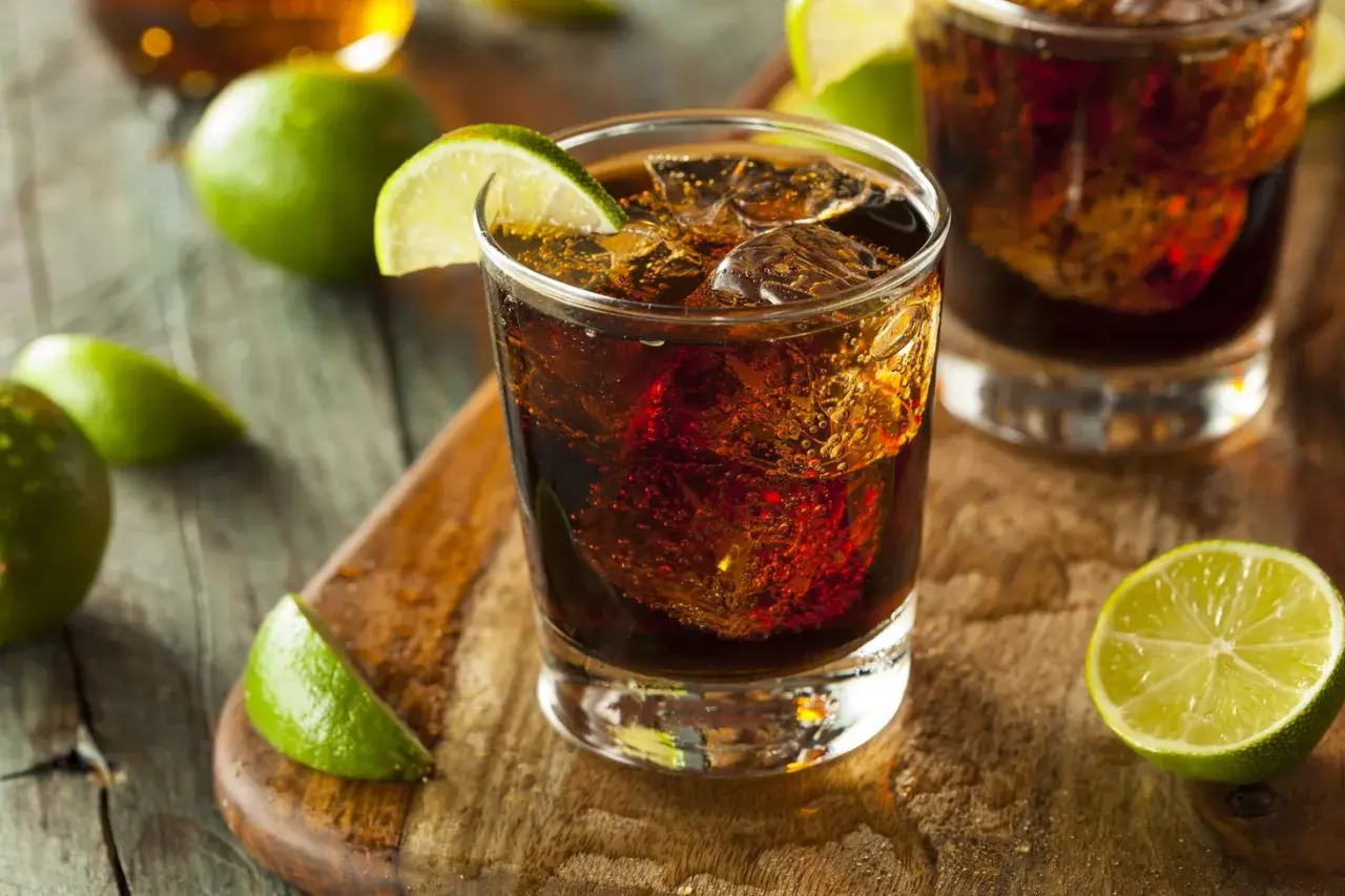 Orzeźwiający drink z rumem Bacardi Raspberry, lodem i limonką na drewnianej desce.
