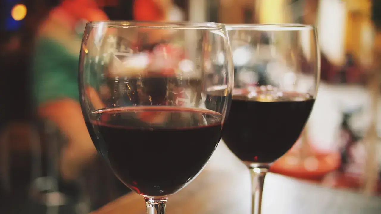 Dwa kieliszki czerwonego wina, być może słodkiego muscat alkohol, na rozmazanym tle.