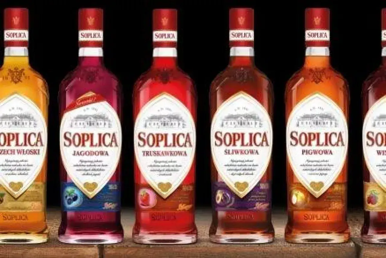 Rząd butelek Soplicy: jagodowa, truskawkowa, śliwkowa, pigwowa i inne smaki.