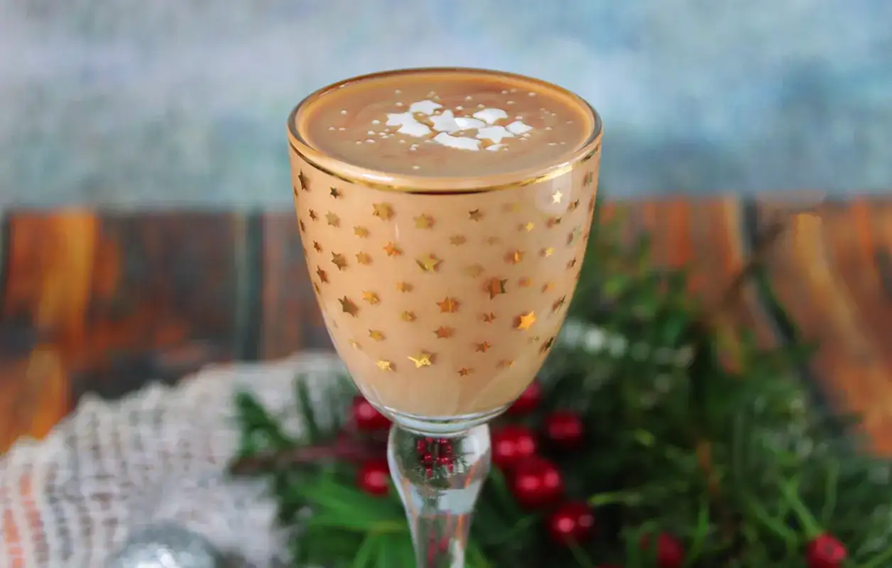 Kukułka alkohol w kieliszku w gwiazdki, ozdobiona pianką i posypką. W tle świąteczne dekoracje.