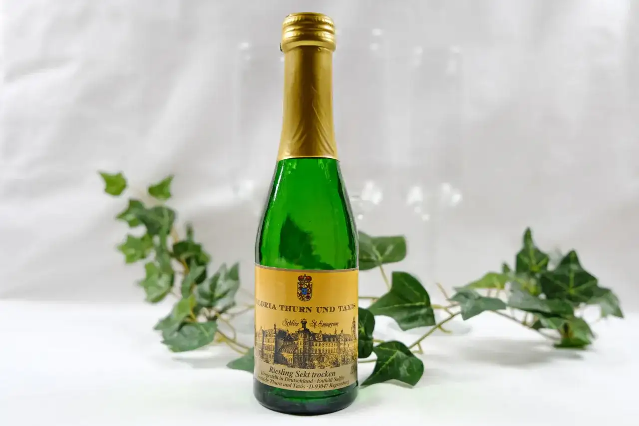 Butelka piccolo z zielonego szkła z etykietą "Riesling Sekt trocken" od Gloria Thurn und Taxis. Czy piccolo ma alkohol? Tak, to wino musujące.