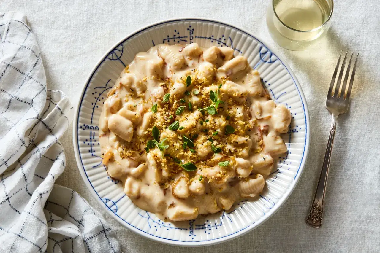 Pyszne gnocchetti w kremowym sosie, posypane chrupiącą panierką i świeżymi ziołami, czekają na talerzu.