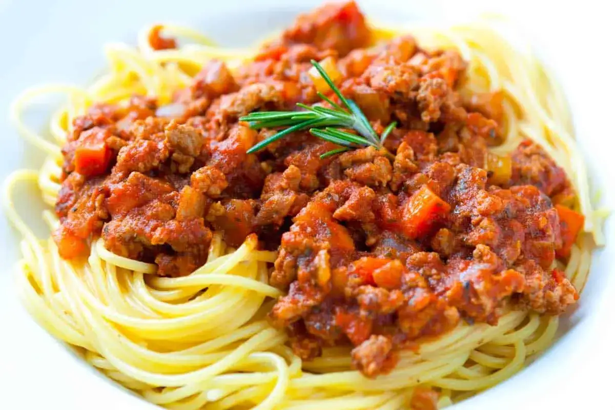 Pyszne spaghettoni z sosem bolońskim i gałązką rozmarynu.