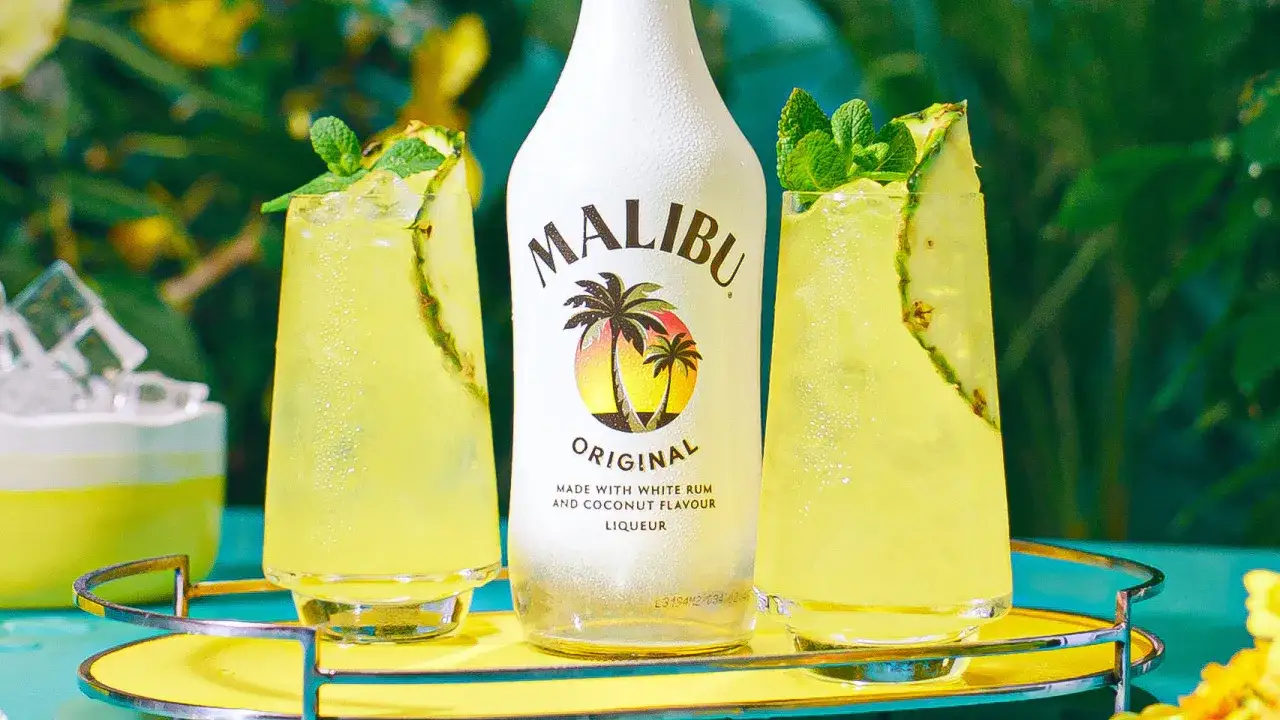 Malibu alkohol: dwa orzeźwiające drinki z ananasem i miętą obok butelki Malibu Original.