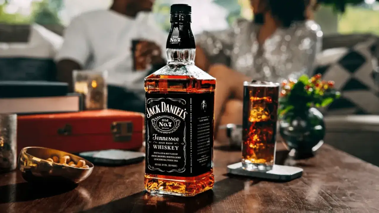 Butelka Jack Daniel's Tennessee Whiskey i szklanka z drinkiem na drewnianym stole. Czy Jack Daniel's to whisky? Tak, to słynna amerykańska whisky.