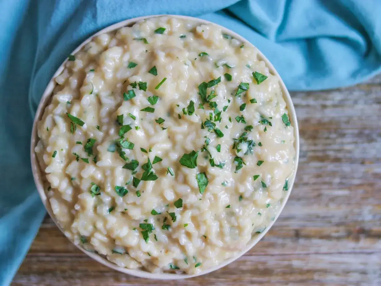 Kremowe włoskie risotto, posypane świeżą natką pietruszki. Idealny przepis na pyszny obiad.