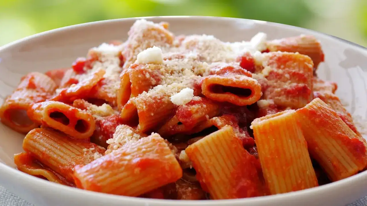 Pyszne bucatini amatriciana w sosie pomidorowym, posypane parmezanem.