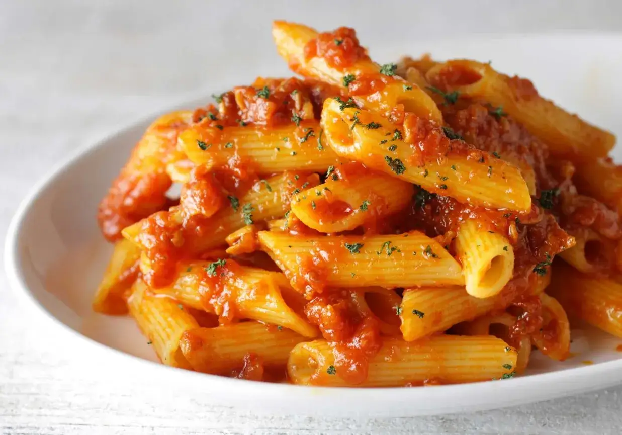Penne rigate w pikantnym sosie pomidorowym, idealne do przygotowania według przepisu arrabiata. Posypane natką pietruszki.