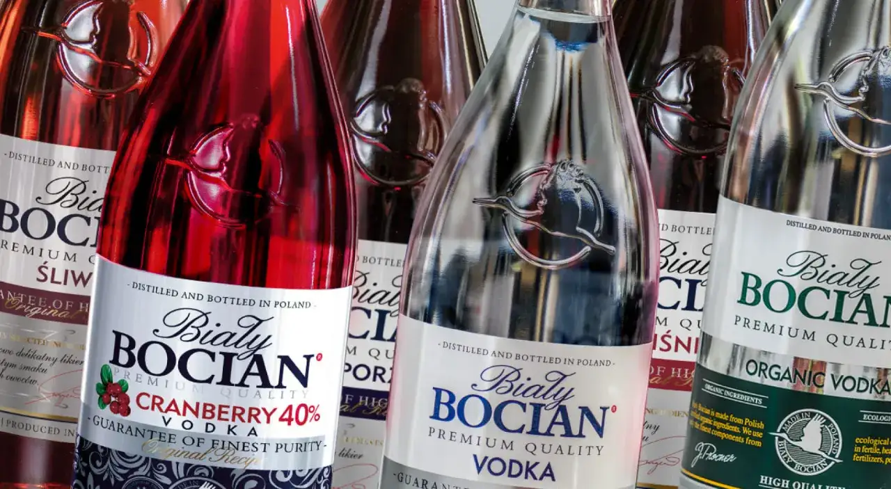 Butelki wódki Biały Bocian: jedna z żurawiną 40%, druga śliwkowa, trzecia czysta.