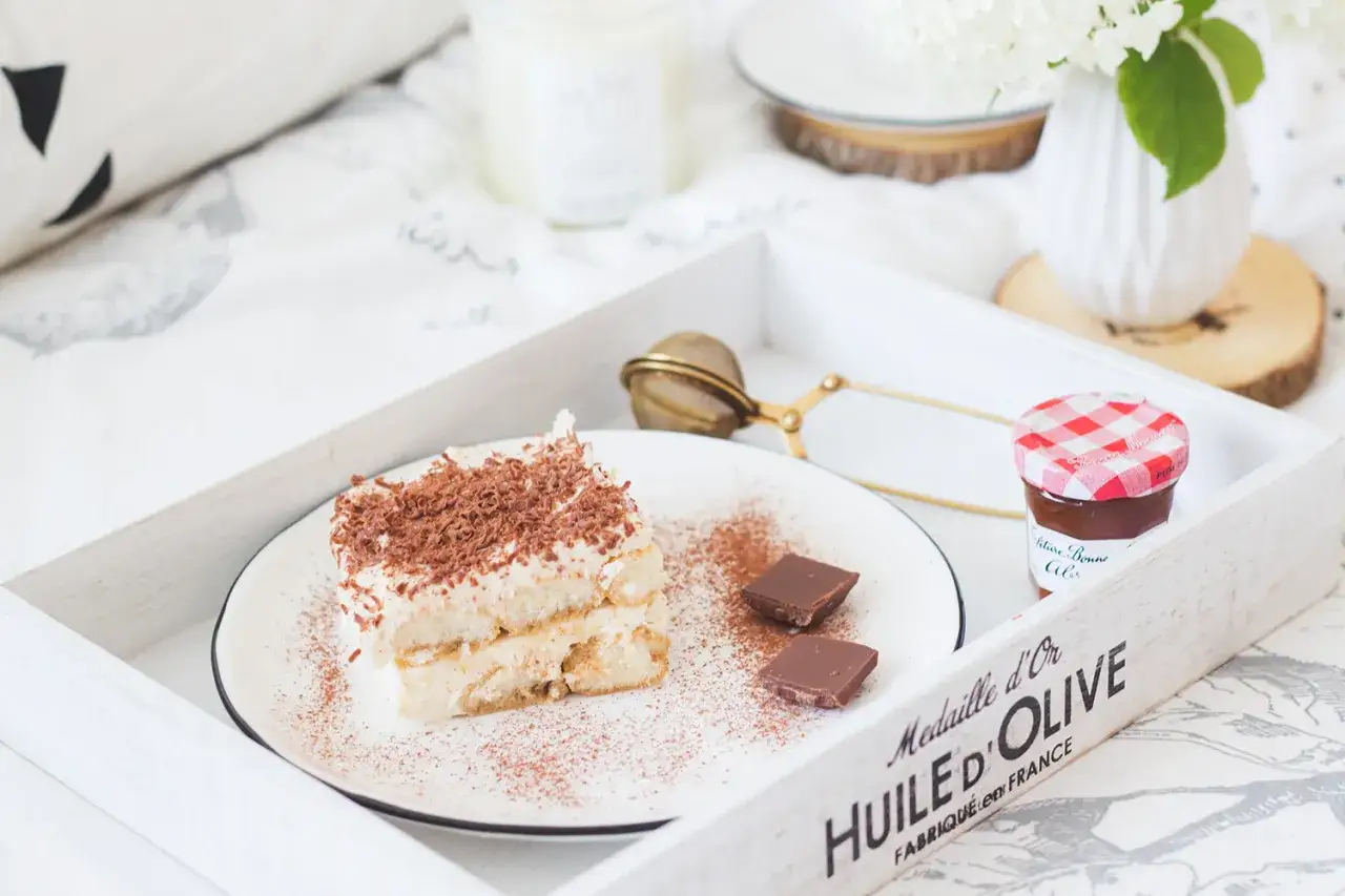 Pyszne tiramisu z wiórkami czekolady i dwoma kostkami gorzkiej czekolady. Zastanawiasz się, jaki alkohol do tiramisu? Może amaretto lub likier kawowy?