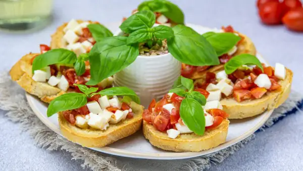 Przepis na bruschettę z pomidorami i mozzarellą: chrupiące grzanki z soczystymi pomidorami i kremową mozzarellą, ozdobione świeżą bazylią.