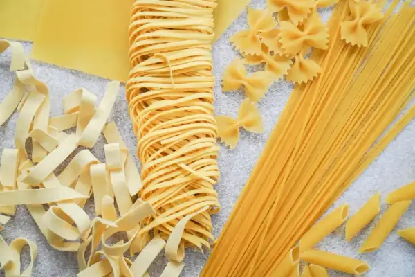 Różne rodzaje makaronu: tagliatelle, spaghetti, farfalle i penne. Idealne do przygotowania pysznego obiadu, ale warto pamiętać o ich kaloryczności.
