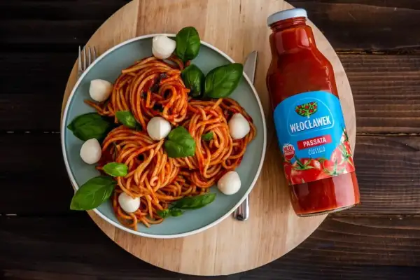 Pyszne spaghetti z kulkami mozzarelli i bazylią, obok butelka passaty pomidorowej Włocławek. Idealny składnik do sosu.