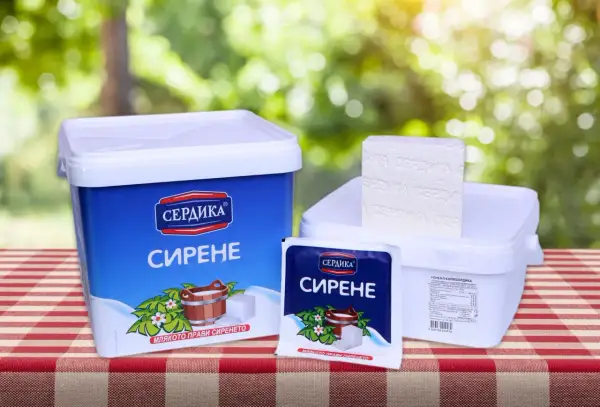 Ser bawoli na stole, w niebieskim i białym opakowaniu, obok kostki sera.