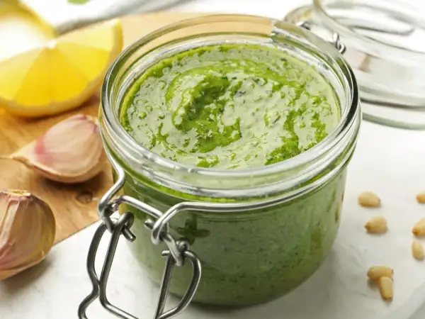 Domowe pesto w słoiku, obok czosnek i cytryna. Czy pesto ze słoika się podgrzewa? Zwykle nie, ale to zależy od przepisu.