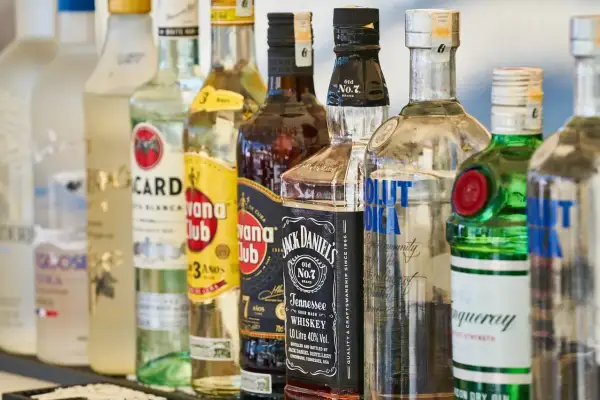 Różne rodzaje wódki i alkoholi, w tym Bacardi, Havana Club, Jack Daniel's, Absolut Vodka i Tanqueray, stoją w rzędzie.