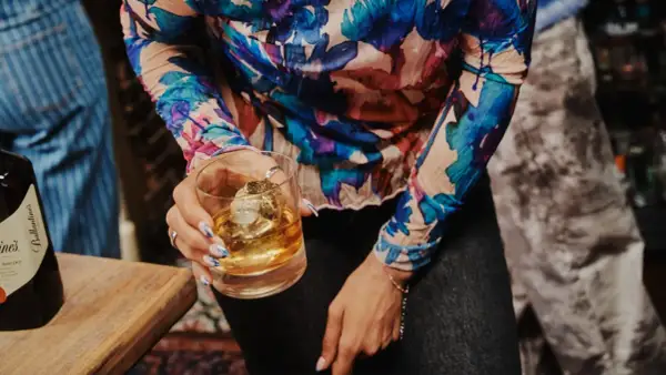 Kobieta trzyma szklankę z whisky Ballantine's. Zastanawia się, ile procent ma ten wyborny trunek.