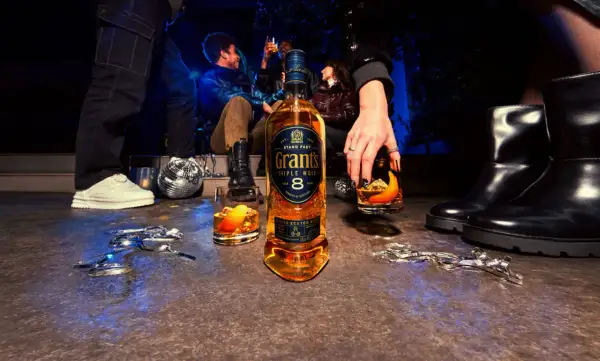 Impreza w toku, butelka Grant's Triple Wood 8 Years i drinki z pomarańczą.