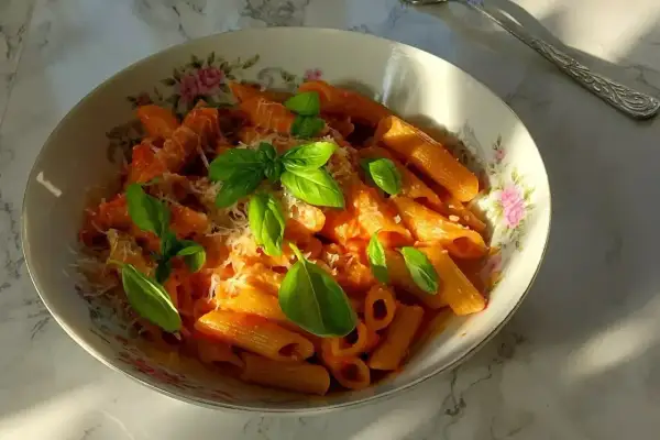 Penne all'arrabiata co to? Pikantny sos pomidorowy z czosnkiem i chili, podany z makaronem penne, posypany parmezanem i świeżą bazylią.